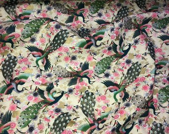 Könnte beinhalten: Ein cremefarbener Stoff mit einem sich wiederholenden Muster aus Pfauen und rosa Blüten. Die Pfauen sind grün, blau und goldfarben mit filigranen Details. Die Blüten sind stilisiert und haben ein zartes Aussehen.