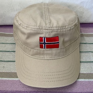 May include: A beige cotton baseball cap with a red, white, and blue embroidered Norwegian flag on the front.