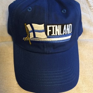 May include: A blue baseball cap with an embroidered Finnish flag and the word "FINLAND" on the front.