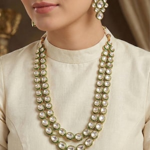 May include: A two-strand necklace with green and gold accents and white stones. Matching earrings with the same design are included.