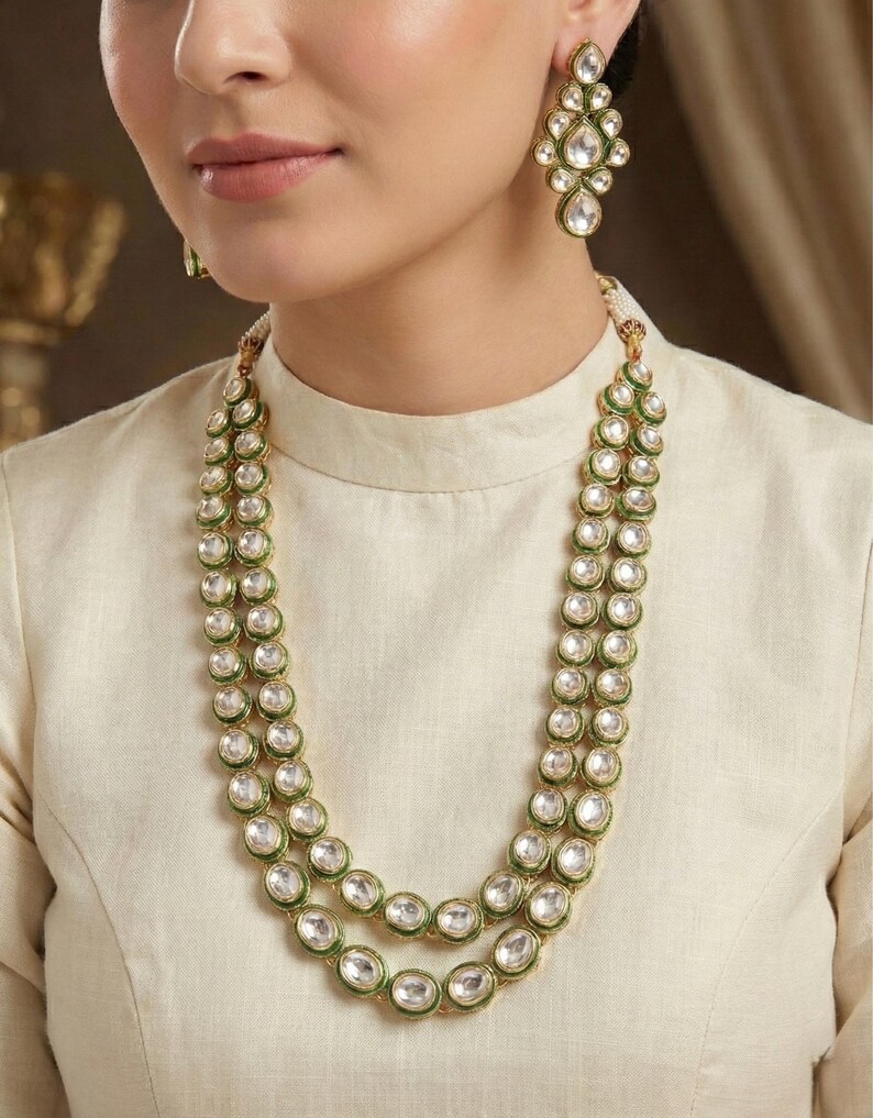 May include: A two-strand necklace with green and gold accents and white stones. Matching earrings with the same design are included.