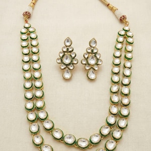 May include: A two-strand necklace with green and gold accents and white stones. Matching earrings with the same design are included.