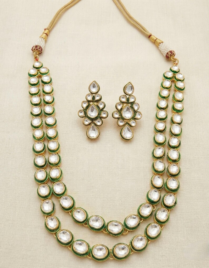 May include: A two-strand necklace with green and gold accents and white stones. Matching earrings with the same design are included.