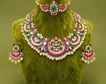 May include: A jewelry set consisting of a necklace, a choker, and a pair of earrings. The pieces feature gold-tone metal, pink and green stones, clear crystals, and small white pearls. The necklace has a large central pendant with crescent shapes.
