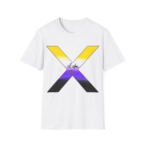 Puede incluir: Camiseta blanca con un gran diseño en forma de X en los colores de la bandera del orgullo no binario: amarillo, blanco, morado y negro. Las palabras "I am me" están escritas en cursiva dentro de la X. La camiseta tiene mangas cortas y cuello redondo.