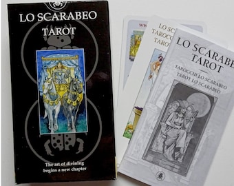 May include: A tarot card deck titled "Lo Scarabeo Tarot" with a black box featuring an image of a chariot pulled by horses. The deck includes cards and a guidebook. The text "The art of divining begins a new chapter" is also visible.