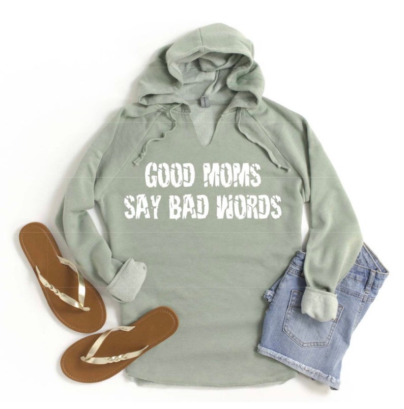 Op de afbeelding: Saliegroen hooded sweatshirt met een V-hals en de tekst "Good Moms Say Bad Words" in wit.