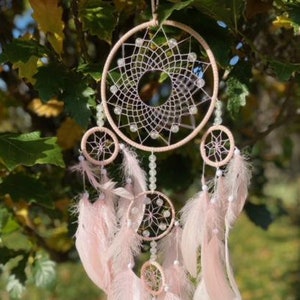 Pretty Pink coloured dream catcher with 5 circles decorated with beads and large hanging pink feathers.