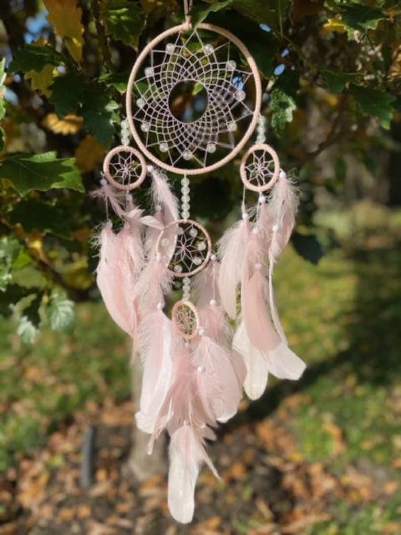 Pretty Pink coloured dream catcher with 5 circles decorated with beads and large hanging pink feathers.