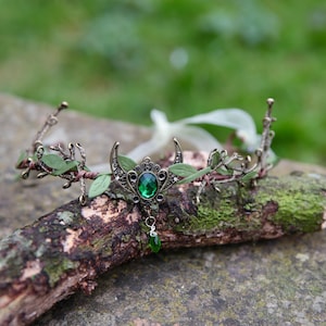 Fairy crown, elven tiara, green foliage, the centre is decorated with a metal crescent moon and green hanging crystal. Adjustable at back with a ribbon tie.