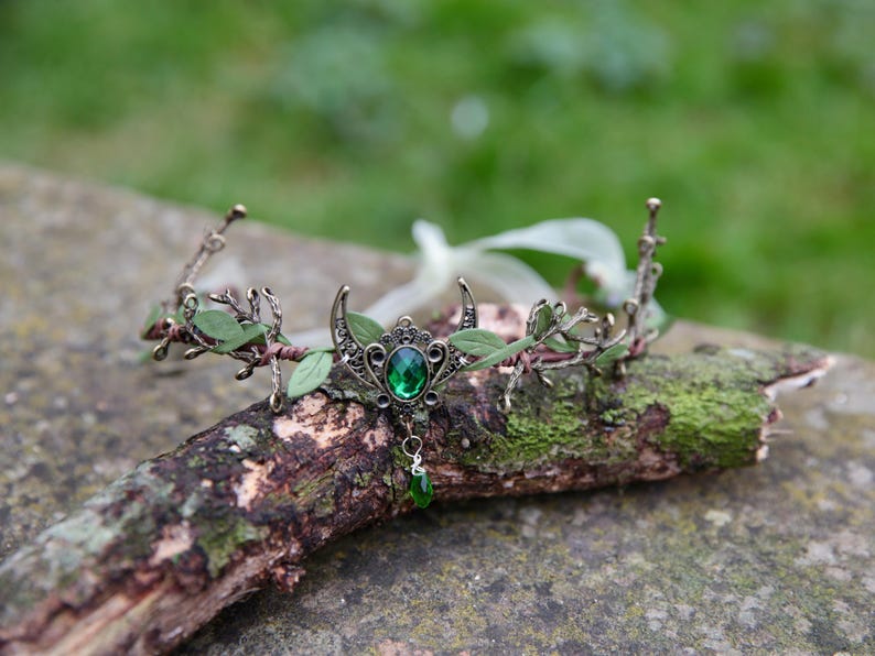 Fairy crown, elven tiara, green foliage, the centre is decorated with a metal crescent moon and green hanging crystal. Adjustable at back with a ribbon tie.