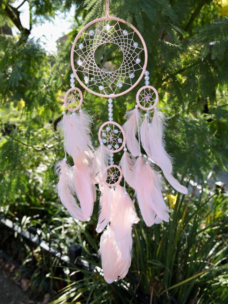 Pretty Pink coloured dream catcher with 5 circles decorated with beads and large hanging pink feathers.