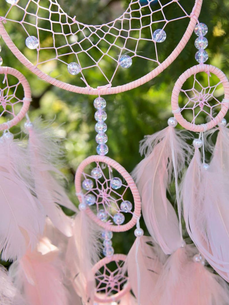 Pretty Pink coloured dream catcher with 5 circles decorated with beads and large hanging pink feathers.