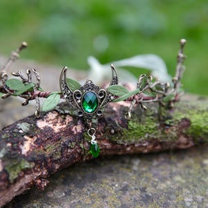 Fairy crown, elven tiara, green foliage, the centre is decorated with a metal crescent moon and green hanging crystal. Adjustable at back with a ribbon tie.