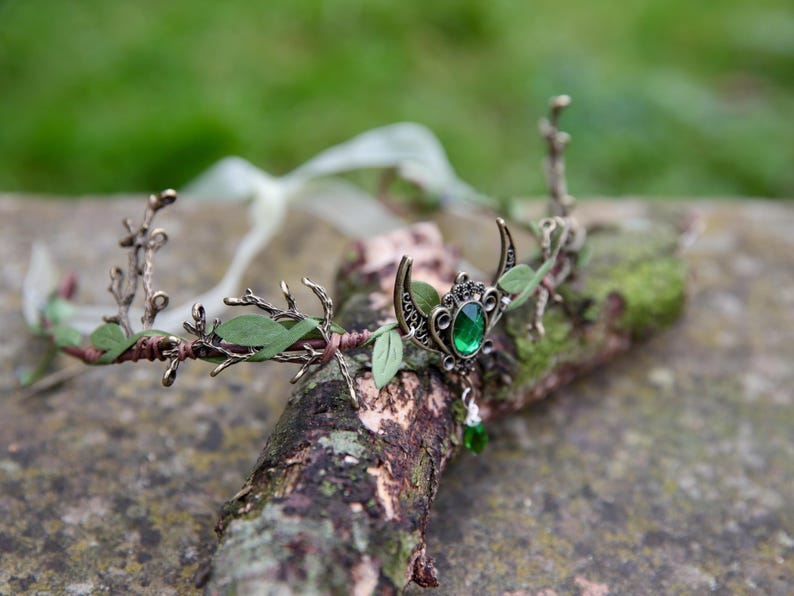 Fairy crown, elven tiara, green foliage, the centre is decorated with a metal crescent moon and green hanging crystal. Adjustable at back with a ribbon tie.