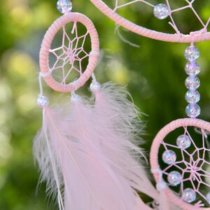 Pretty Pink coloured dream catcher with 5 circles decorated with beads and large hanging pink feathers.