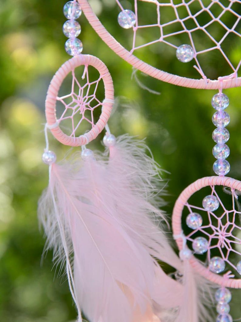 Pretty Pink coloured dream catcher with 5 circles decorated with beads and large hanging pink feathers.