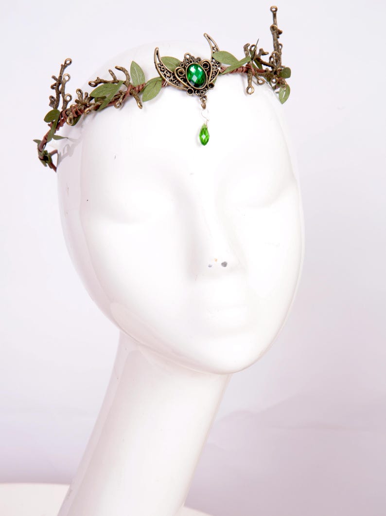 Fairy crown, elven tiara, green foliage, the centre is decorated with a metal crescent moon and green hanging crystal. Adjustable at back with a ribbon tie.