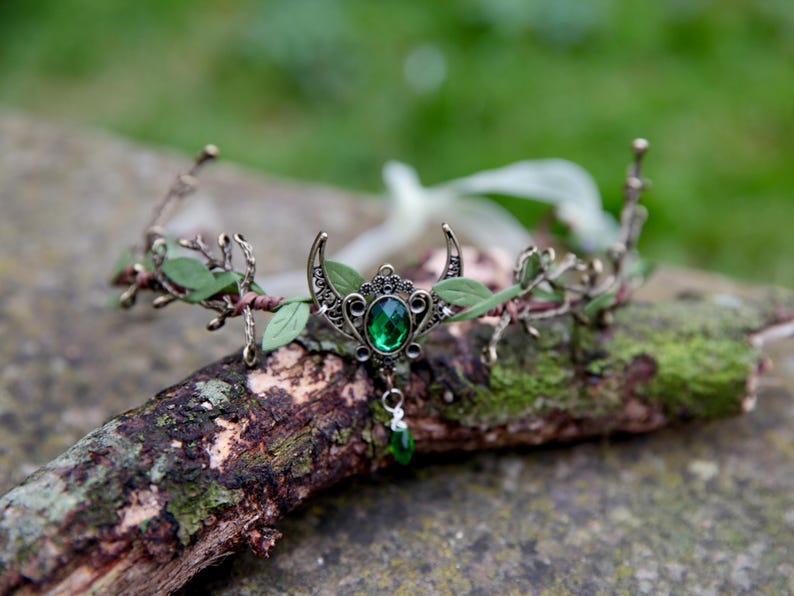 Fairy crown, elven tiara, green foliage, the centre is decorated with a metal crescent moon and green hanging crystal. Adjustable at back with a ribbon tie.