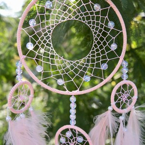 Pretty Pink coloured dream catcher with 5 circles decorated with beads and large hanging pink feathers.