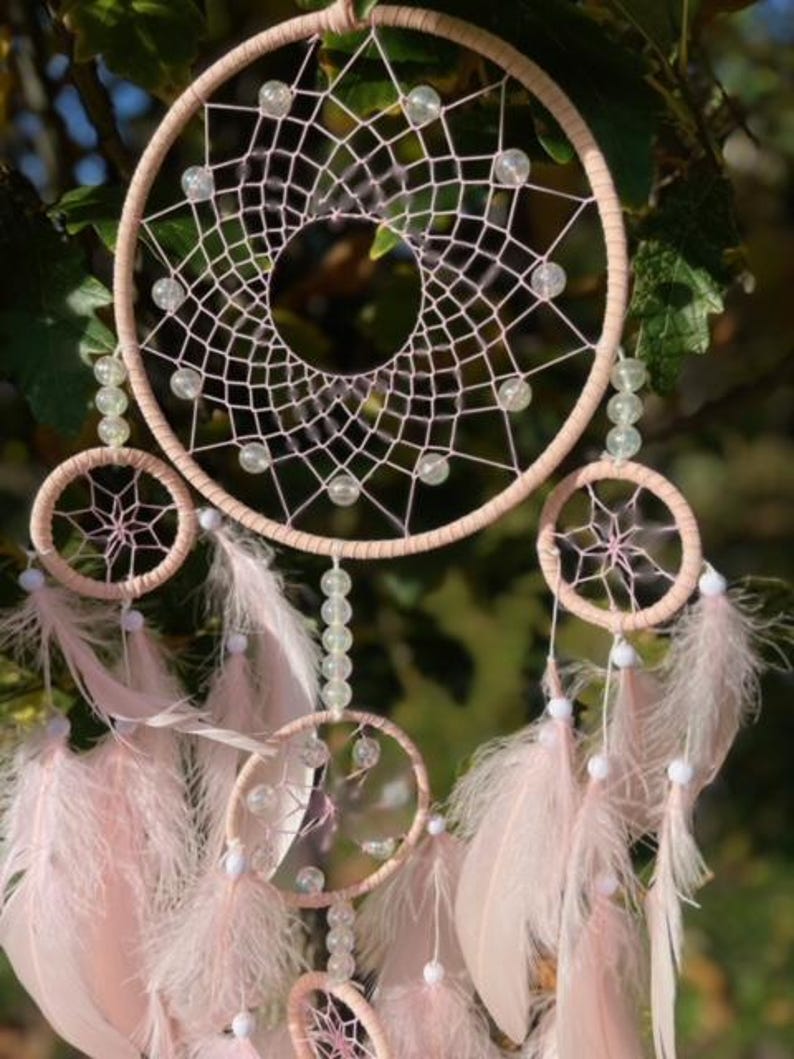 Pretty Pink coloured dream catcher with 5 circles decorated with beads and large hanging pink feathers.