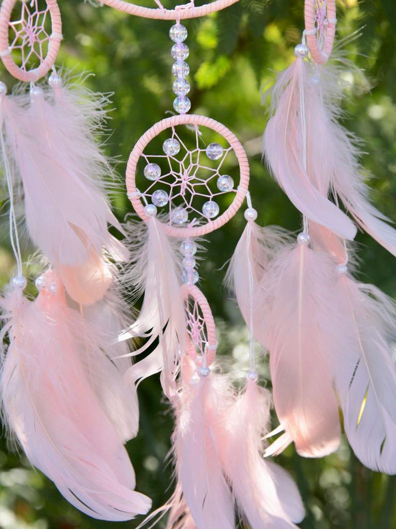 Pretty Pink coloured dream catcher with 5 circles decorated with beads and large hanging pink feathers.