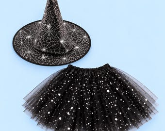 Puede incluir: Un sombrero puntiagudo negro con un patrón de telaraña blanco y una falda de tul negra a juego adornada con un estampado de purpurina plateada de estrellas y lunas crecientes. El conjunto incluye un sombrero de ala ancha y una falda fruncida.