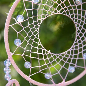 Pretty Pink coloured dream catcher with 5 circles decorated with beads and large hanging pink feathers.
