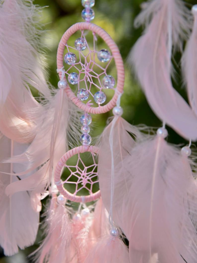 Pretty Pink coloured dream catcher with 5 circles decorated with beads and large hanging pink feathers.