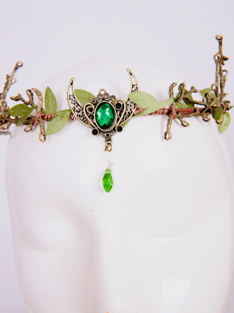 Fairy crown, elven tiara, green foliage, the centre is decorated with a metal crescent moon and green hanging crystal. Adjustable at back with a ribbon tie.