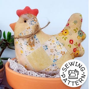 May include: A patchwork fabric chicken with a red comb and a floral pattern. The chicken is sitting in a terracotta pot with a lace trim. The image includes the text "Sewing Pattern".