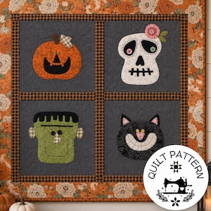 May include: A square wall hanging quilt featuring four appliqued Halloween characters: an orange pumpkin, a white skull with a pink flower, a green monster, and a black cat. The quilt has a dark gray background, a black and brown houndstooth border, and an outer border with an orange floral pattern.