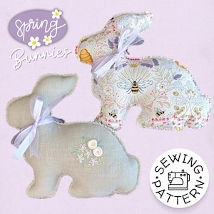 May include: Two stuffed bunny decorations. One is light gray with embroidered flowers and a lavender ribbon. The other is patterned with bees and flowers, and has a lavender ribbon. The image includes the text "Spring Bunnies".