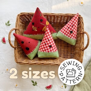 May include: Four watermelon-shaped fabric items in a wicker basket. Two are red with black seed details, one with a dragonfly pattern. The other two are red and white checkered. The text "2 sizes" is visible.
