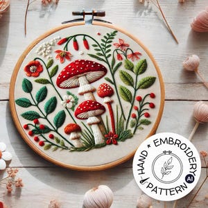 May include: Embroidered hoop art featuring a whimsical forest scene with red and white mushrooms, green leaves, and red berries. The hoop is made of wood and has a white fabric background. The text "Hand Embroidery Pattern" is printed on a white circle below the hoop.