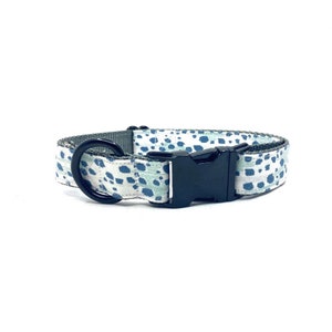 May include: A white dog collar with a blue and green abstract pattern and a black plastic buckle.