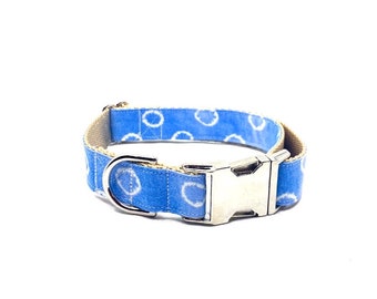 Puede incluir: Un collar de perro azul con un patrón de círculos blancos y una hebilla plateada.