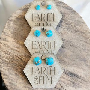 May include: Three pairs of turquoise stud earrings displayed on hexagonal cards with the text "Earth and Elm".