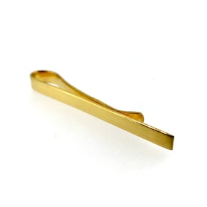 May include: A gold-colored tie clip with a simple, sleek design.
