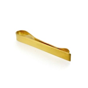 May include: A gold-colored tie clip with a simple, sleek design.