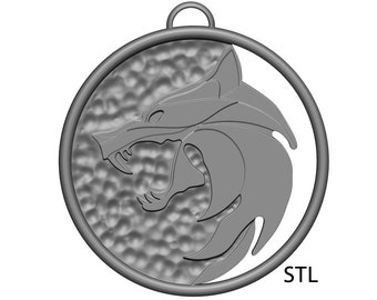 May include: A silver pendant with a wolf head design. The pendant is round and has a textured surface. The wolf head is facing to the right and has a sharp, aggressive look. The pendant is labeled "STL".