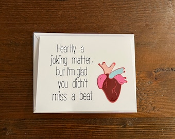 May include: A white card with a red heart illustration and the text "Heartly a joking matter, but I'm glad you didn't miss a beat."