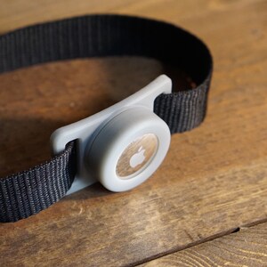 May include: A gray Apple Watch band with a black strap and a silver buckle.