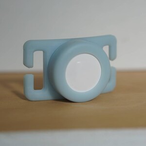 May include: A light blue plastic baby teether with a white circle in the center.