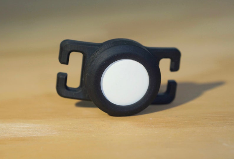 May include: A black plastic safety light with a white reflective disc. The light has a clip for attaching to clothing or a backpack.