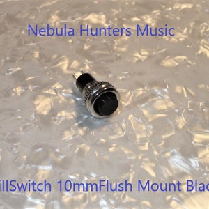 May include: A black KillSwitch button with a 10mm flush mount, set against a textured, off-white background. The button is surrounded by a silver metal ring. The text "Nebula Hunters Music" and "KillSwitch 10mm Flush Mount Black" are visible.