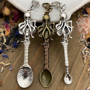 Puede incluir: Tres cucharas de encanto de pulpo de plata, bronce y cobre con mangos envueltos en alambre. Los encantos de pulpo están detallados con tentáculos y ojos. Las cucharas son pequeñas y tienen un cuenco redondeado.