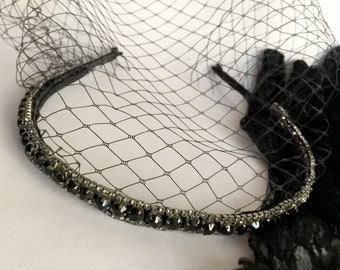 Puede incluir: Una diadema negra con una fila de piedras de cristal negras y un velo de tul negro.