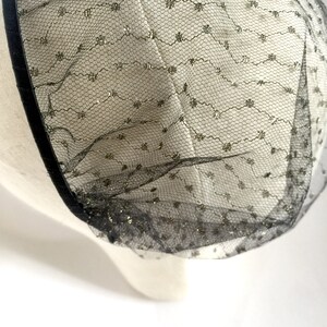 May include: Black tulle fabric with gold glitter accents. The tulle is gathered and has a black ribbon trim.