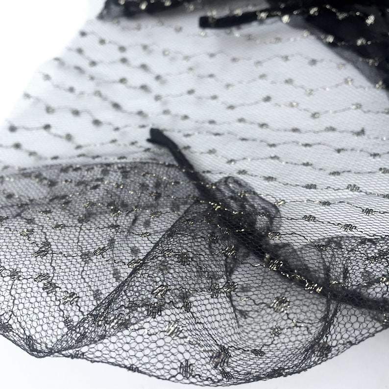 May include: Black tulle fabric with silver glitter dots. The fabric has a ruffled edge.